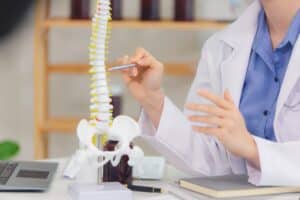 A doctor pointing to a model of the spine and discussing spinal cord injuries